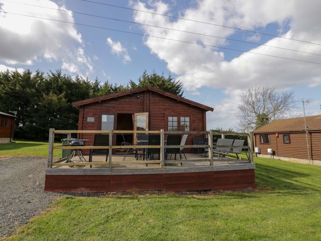 A log cabin with a deck and chairs at Holly Lodge Evesham
