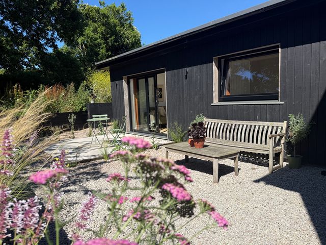 A garden with a wooden bench and table at Birdsong in Gulval