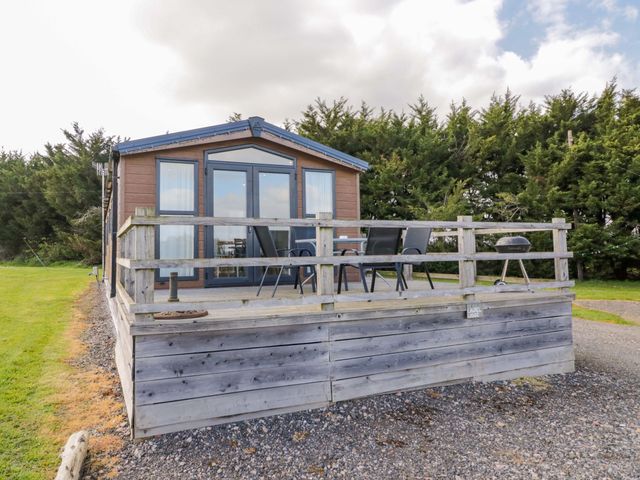A cabin with a deck and chairs at Laurel Lodge Offenham