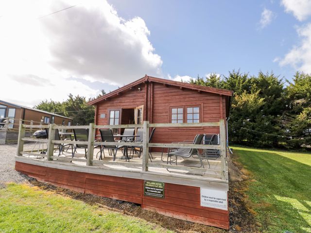 A lodge with a deck and chairs at Oak Lodge Offenham
