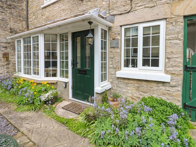 An entrance with a green door and windows at Wedgewood Cottage in Middleham