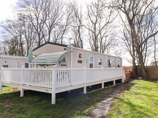 A caravan with a deck and umbrella at Sunflower Retreat, Caravan 61