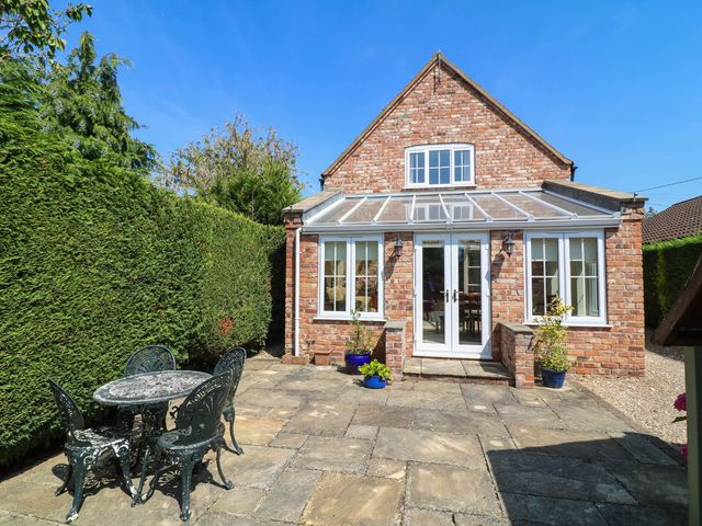 A conservatory with a table and chairs in the garden at Wisteria House in Lincoln