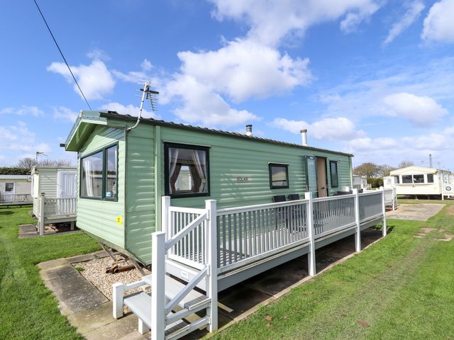 A green caravan with a deck and steps at The Seafront Cosy Caravan in Ingoldmells