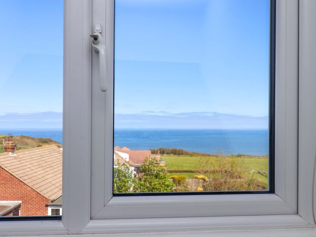A window view of the ocean and landscape at Cozy Cottage