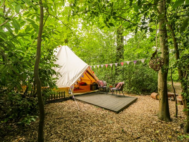 A bell tent with chairs and a table in an outdoor area at Bedouin Bell Tent in Woolton Hill