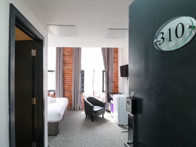A bedroom with a bed and armchair at Apartment 310 in Nottingham