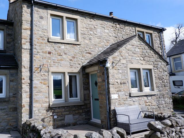 A stone house exterior with windows and a seating area at 2 Rock View near Settle