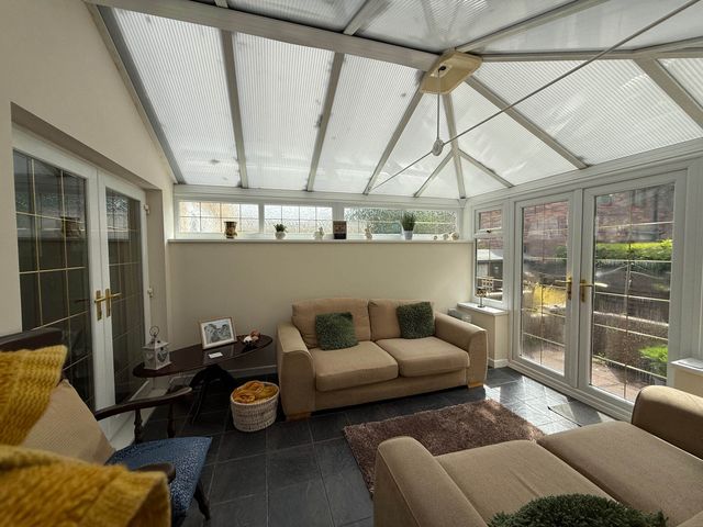 A conservatory with a sofa and table at 3 Bed House - Sleeps 6 - Parking - Garden - Wifi Glynneath