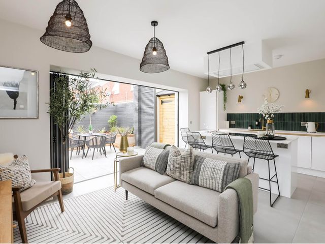 A living room with a sofa and kitchen area at Luxury 2 Bed Home w/ Spa-like Ensuites & Patio Hereford