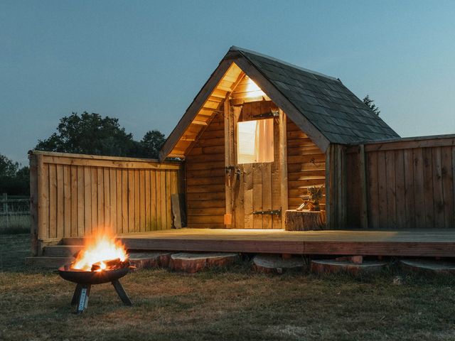 A wooden cabin with a fire pit outside at Glamping at the Retreat Wiltshire Christian Malford
