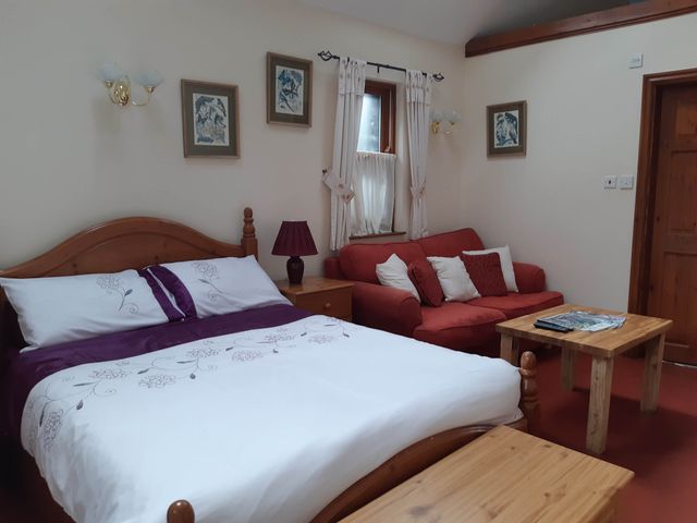 A bedroom with a bed and sofa at Beautiful 1-Bed Cottage in Trellech