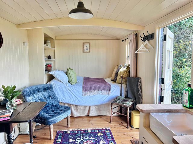 A cozy room with a bed and table at Cozy Cabin Retreat near Chepstow
