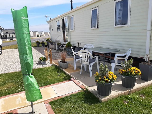 An outdoor area with a table, chairs, and flower planters at Taid's Retreat Silversands Cove beach lossiemouth
