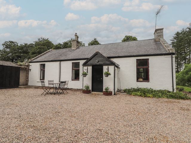 An outdoor view of a house with a table and chairs at Keepers Cottage in New Deer