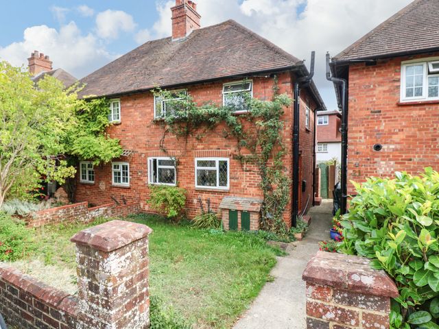 A brick house with a garden and pathway at Daisy Cottage Dorking
