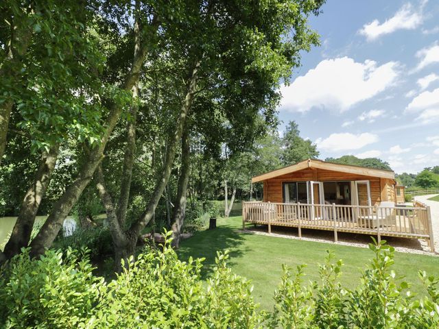 A cabin with a deck surrounded by trees and grass at Skylark in Ross-on-Wye