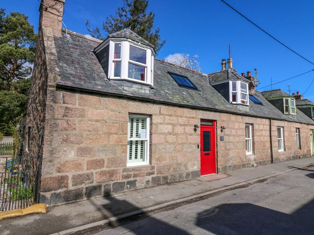 A stone house with a red front door at Evansford in Ballater