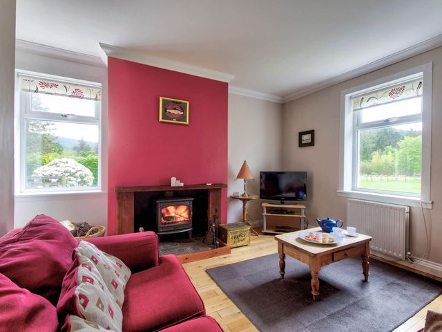 A living room with a fireplace and a television at Argyll Farmhouse-Idyllic Setting-Sleeps10 in Dunoon