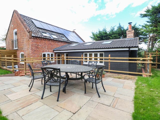 A patio area with a table and chairs at Bramley Cottage in Worlingham