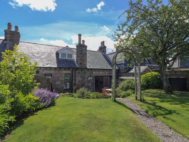 A garden with a house and archway at St Kilda in Ballater