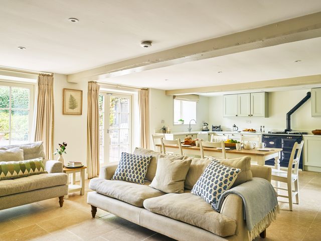 A living room with a sofa and kitchen area at Gitcombe Coach House in Totnes