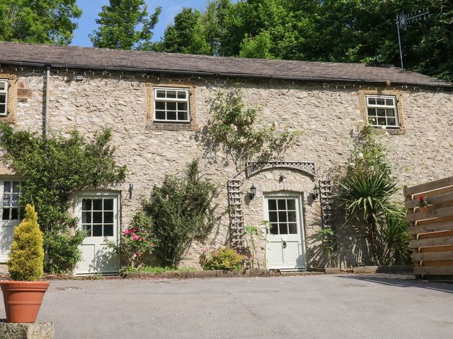 A stone exterior with windows and doors surrounded by greenery at The Barn 