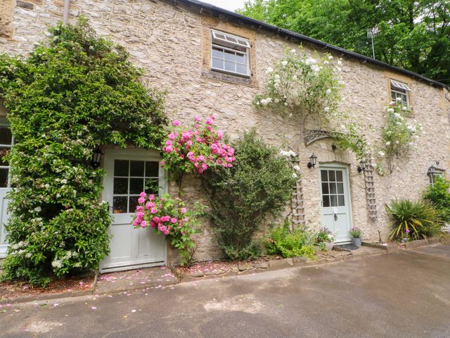 An outdoor area with stone walls and flowering plants at The Barn in Miller's Dale near Tideswell
