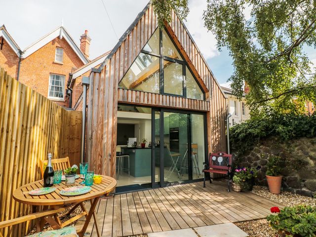A garden with a wooden deck and seating area at Little Mornington in Malvern