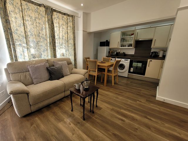 A living room with a sofa and kitchen area at Palace Court 