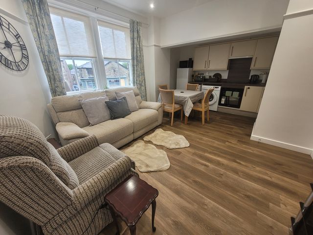 A living room with a sofa and dining area at Palace Court in Buxton