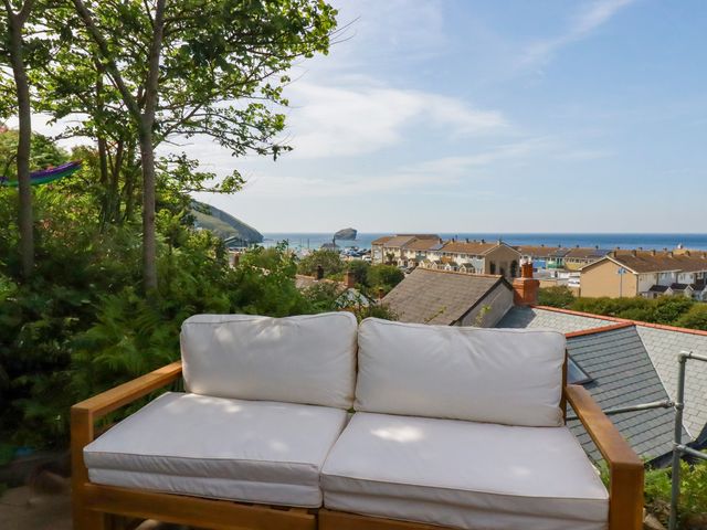 A sofa with a view of the sea and houses at 18 Tregea Terrace in Portreath