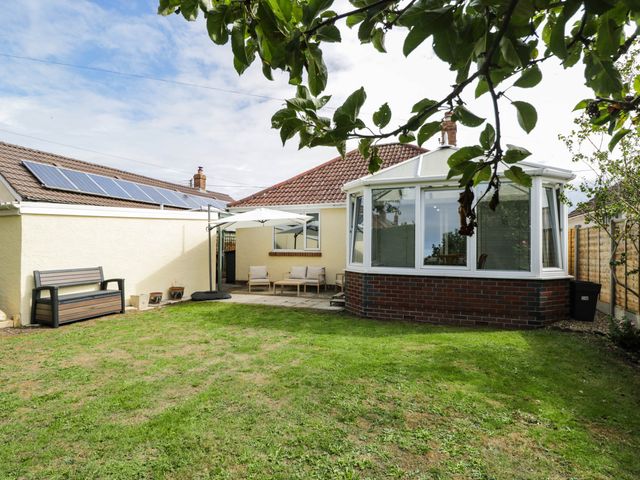 A garden with a conservatory and outdoor furniture at 3 Station Road in Weston-Super-Mare