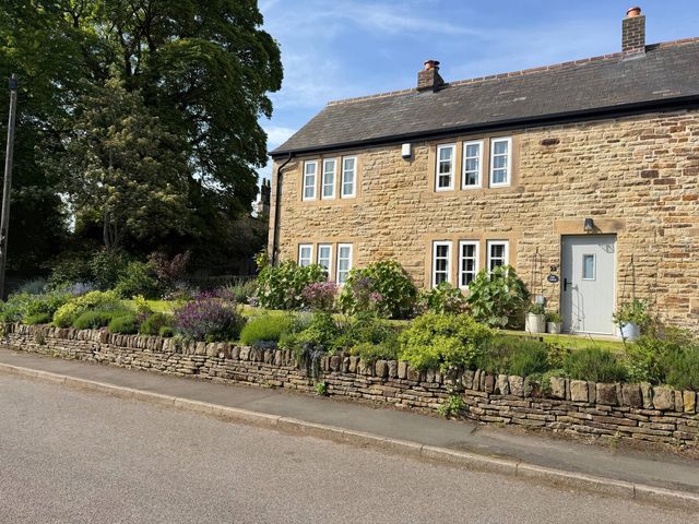 A stone house with a garden and a front door at Holly Cottage in Totley