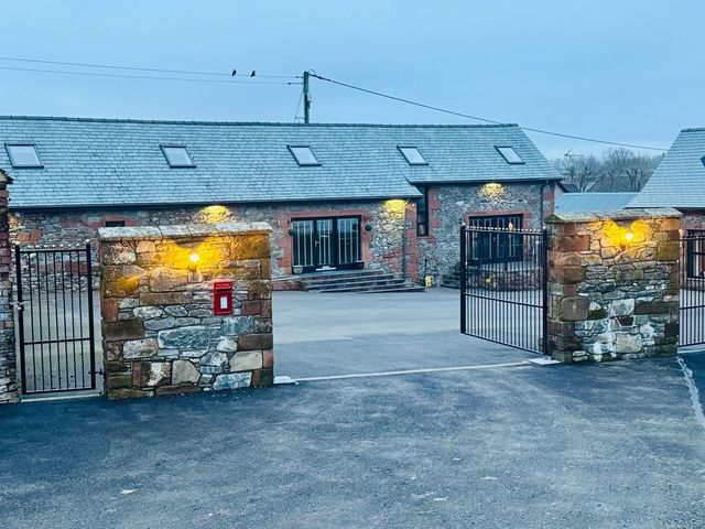 An outdoor view of a property entrance with a stone wall and gate at The Steading in Dumfries