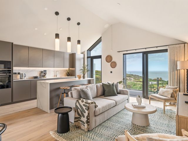A living room with a sofa and kitchen area at tbc in St. Ives