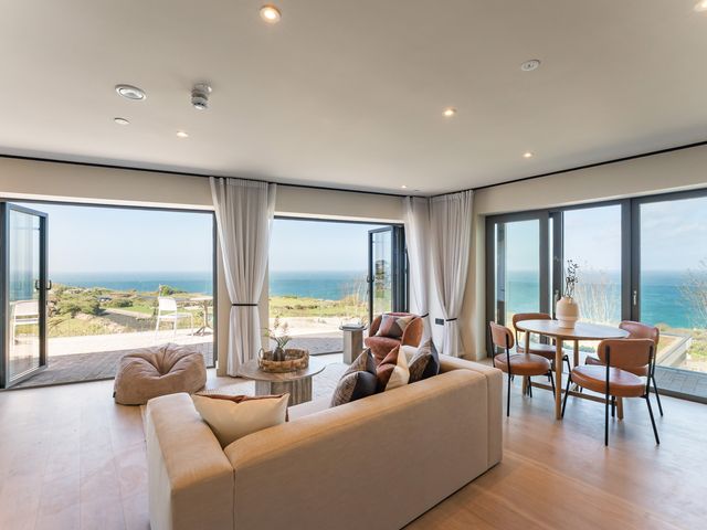A living room with a sofa and table overlooking the ocean at tbc in St. Ives