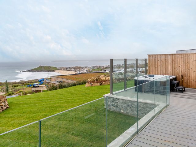 An outdoor area with a hot tub and grass overlooking the sea at tbc in St. Ives