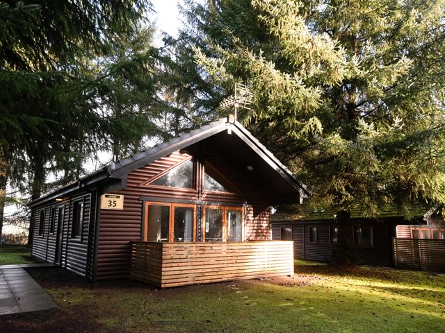 A cabin with wooden exterior and balcony at Sidlaw (Pet) Fowlis near Dundee