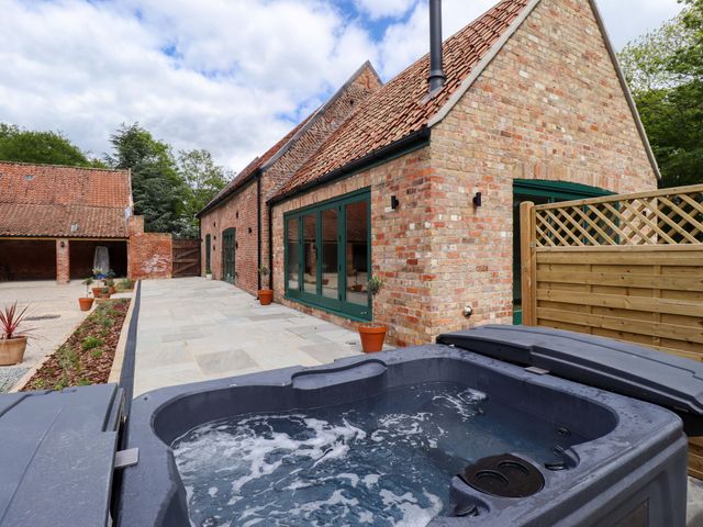A hot tub on a paved patio at Bobblehat Barn in Alford