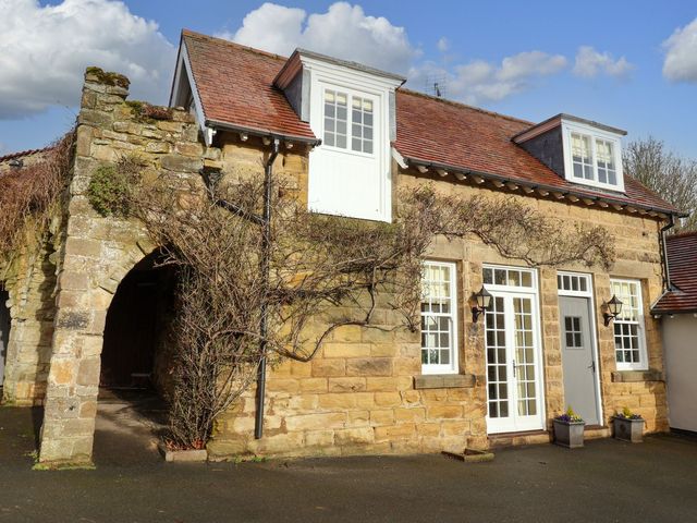 An exterior view of a house with an archway and plants at The Bothy Knaresborough