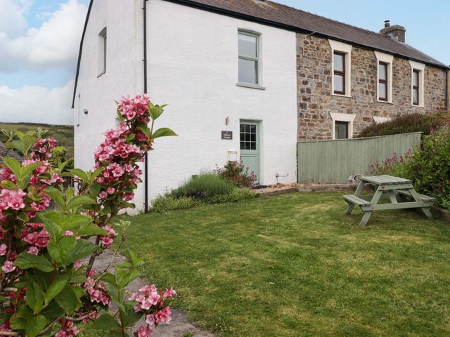 A house with a picnic table and flowers at No.8 Millmoor Farm Cottage in Broad Haven