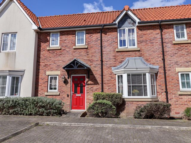 A house facade with a red door and windows at 4 Perran Court in Filey