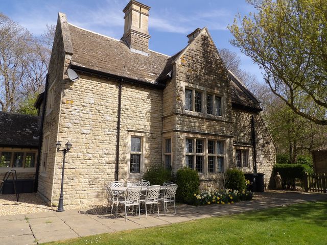 A stone house with a table and chairs in the garden at Greenwood Manor in Peterborough
