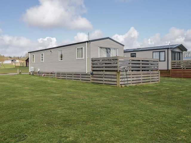 A mobile home with a fence and grass at Fanfare Superior at Three Lochs Holiday Park Newton Stewart