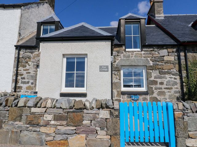 A house with a stone wall and blue gate at Post Cottage in Arisaig