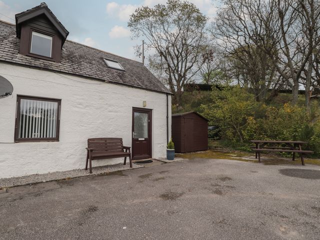 An outdoor area with a house, bench, and shed at 3 Bruaich Cottages near Strathpeffer