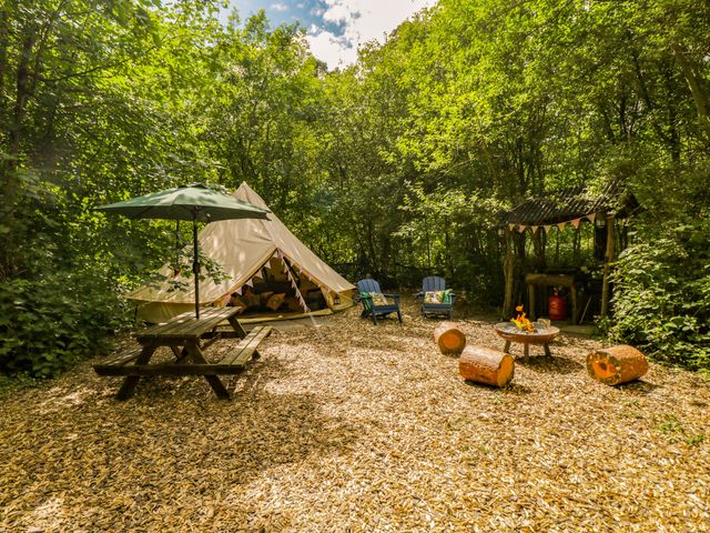 An outdoor area with a tent, chairs, and a picnic table at Jungle Bell Tent in Woolton Hill