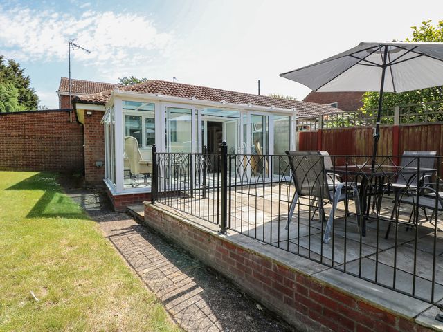 A garden with a conservatory and seating area at 51 Colin McLean Road Dereham