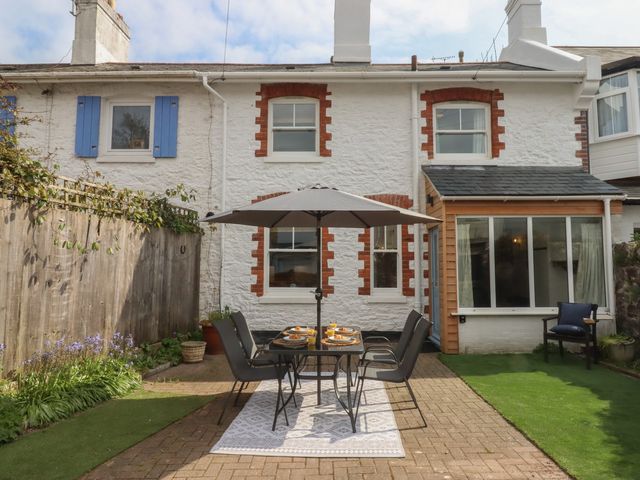 A garden with a table and chairs under an umbrella at Hares Cottage in Torquay